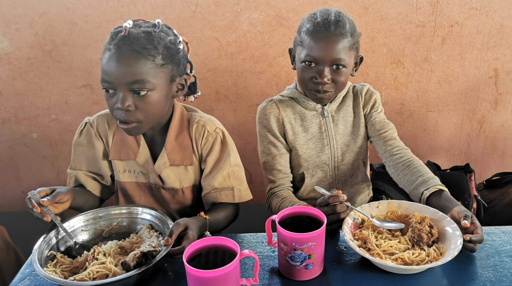 Kameruńskie dzieci jedzą posiłek w szkole