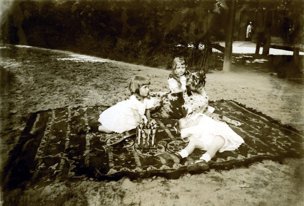 Zdjęcie dzieci księcia Andrzeja Lubomirskiego siedzących w sadzie wraz z psem