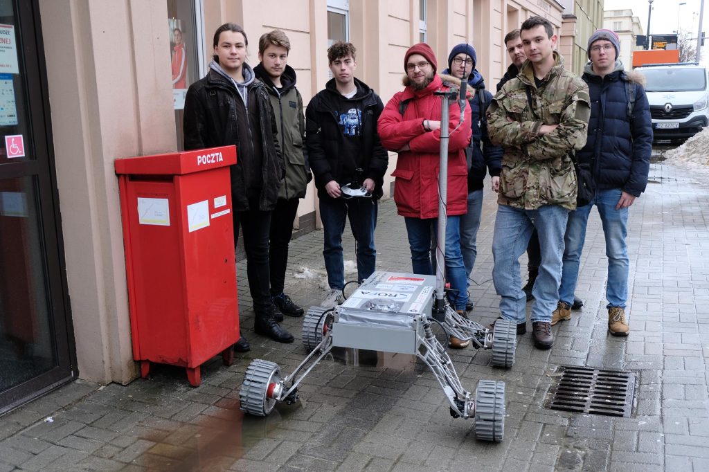 Studenci Politechniki Rzeszowskiej i skonstruowany przez nich łazik przed pocztą w Rzeszowie