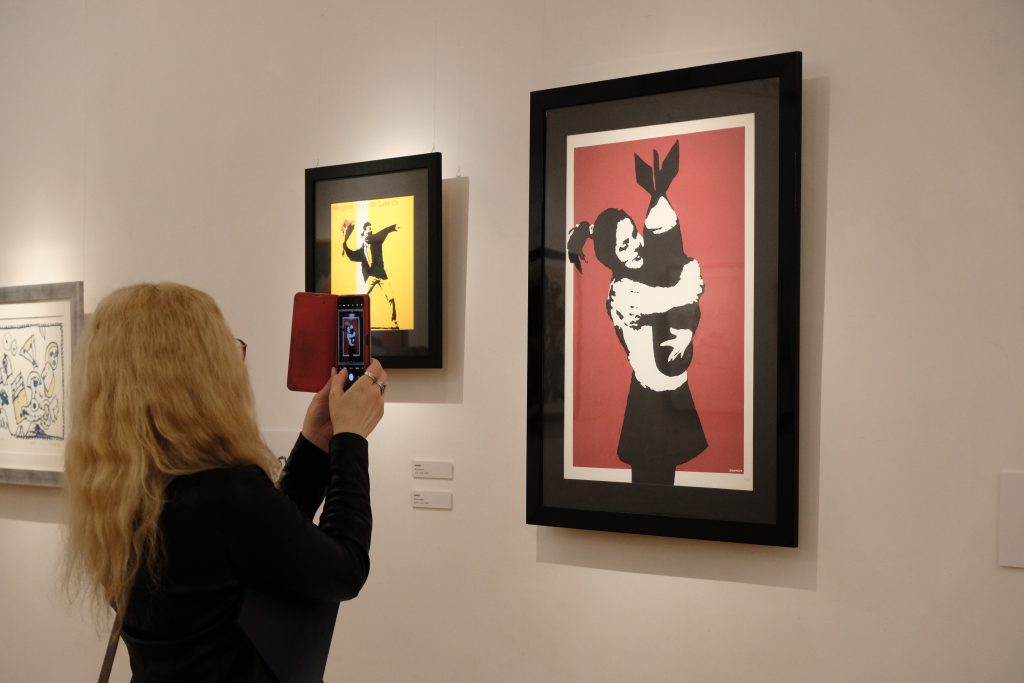 Wśród prac, można zobaczyć m.in. dwie prace słynnego artysty Banksy’ego: Bomb Hugger, przedstawiające dziewczynę trzymającą bombę, oraz prace z serii “We Love You So Love Us” (Fot. Jan Budz). 